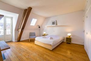 een slaapkamer met een bed, een stoel en een raam bij LA Plume aux pieds du Parvis Saint Jean in Dijon