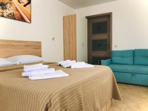 アナパにあるBereg Anapy Guest Houseのベッドルーム1室(ベッド2台、青いソファ付)