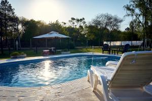 a swimming pool with two chairs and an umbrella at El Rubicón (casa de campo) in Concepción del Uruguay
