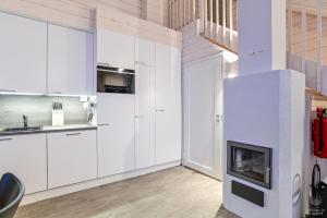 a kitchen with white cabinets and a fireplace at Holiday In Lapland - SointuiLevi B65 in Levi