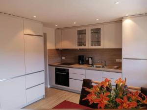 una cocina con armarios blancos y una mesa con flores en Stockerhof en Elzach