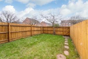a backyard with a wooden fence and a green yard at Coventry- Perchfoot 3 Bedroom Contractor and Pet-Friendly Spacious House By Sublime Stays in Parkside