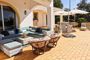 a patio with a couch and chairs and an umbrella at Villa Santa Barbara by Portucasa in Bordeira