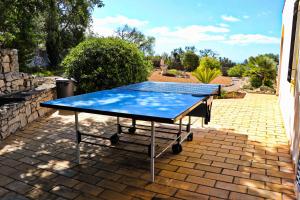 a blue ping pong table on a brick patio at Villa Santa Barbara by Portucasa in Bordeira