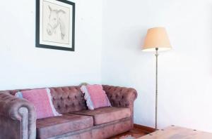 Sofá marrón en la sala de estar con lámpara en Akivillas Ericeira Charm, en Santo Isidoro