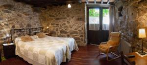 a bedroom with a bed and a chair and a window at Aldea Rural Santo André in Congostro