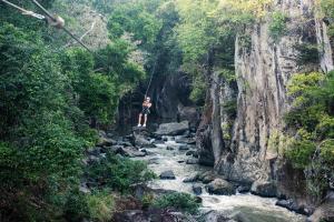 a person on a rope swing over a river at Rio Perdido Hotel & Thermal River in Fortuna