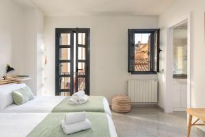 una camera bianca con due letti e una finestra di Flateli Plaça Catalunya 10 a Girona