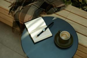 a table with a cup of coffee and a book and a pen at FAV HOTEL ISE in Ise