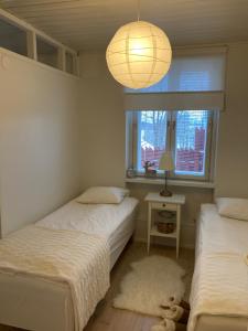 two beds in a room with a window and a lamp at Villa Pyhäjärvi in Tampere