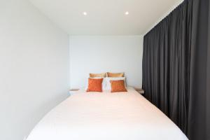 a bedroom with a white bed with orange pillows at Turquoise Turtle Apartment - with seaview and A/C in Sesimbra