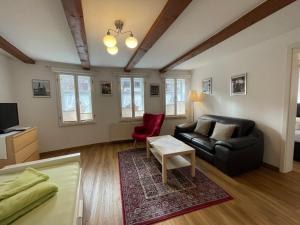 salon z czarną kanapą i czerwonym krzesłem w obiekcie Apartment mit Terrasse No3 w mieście Quedlinburg