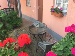 patio z krzesłami, stołem i czerwonymi kwiatami w obiekcie Apartment mit Terrasse No3 w mieście Quedlinburg