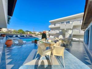 a hotel patio with tables and chairs next to a pool at Sueño beach hotel in Polykhrono