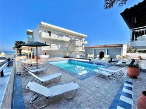 a villa with a swimming pool and lounge chairs at Sueño beach hotel in Polychrono