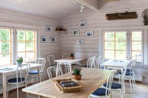 un comedor con mesas, sillas y ventanas en Cafe Alppila, en Iniö