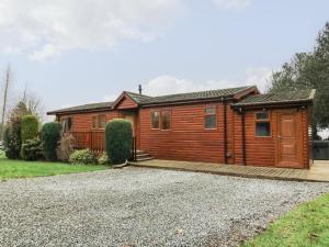 uma grande cabina de madeira com uma entrada de cascalho em 3 The Fairway em Cottingham