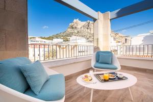a balcony with a chair and a table with a tray of food at Odyssey Rooms Alicante in Alicante