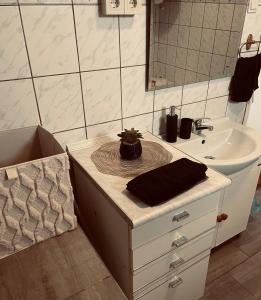 een badkamer met een wastafel en een aanrecht met een spiegel bij Törpi Apartman in Halmaj