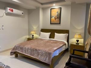 a bedroom with a bed with two lamps and a chair at Marine Tower in Rawalpindi