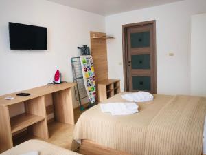 a room with two beds and a desk and a television at Guest House Bereg in Anapa