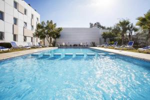 a swimming pool with chairs and a building at Relax Hotel Kenitra in Kenitra