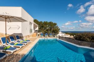 een zwembad met stoelen en een parasol en de oceaan bij Villa Gill in Punta Grossa