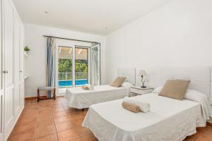 two beds in a room with a window at Villa Es Torrent Verd in Alaior +34 photos