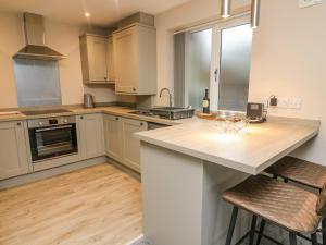 a kitchen with white cabinets and a counter with bar stools at Market Lounge in Clitheroe