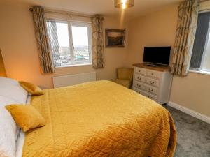 sypialnia z żółtym łóżkiem i telewizorem w obiekcie Market Lounge w mieście Clitheroe