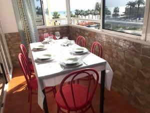 stół z czerwonymi krzesłami, biały stół i okno w obiekcie Costamar, Primera linea de playa, 3 dormitorios, 2 baños, vistas al mar, Internet Wifi y Garaje, Ideal parejas y familias w mieście Benalmádena