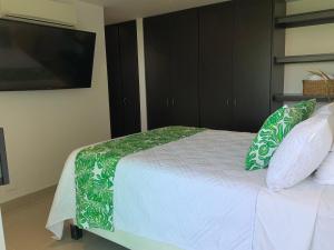 1 dormitorio con 1 cama con almohadas verdes y blancas en Apartamento en Cartagena frente a la playa de Marbella entre el aeropuerto y el centro histórico, en Cartagena de Indias