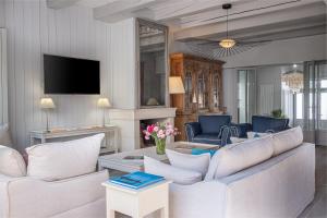 a living room with white furniture and a tv at La Baronnie Villa & Spa in Saint-Martin-de-Ré