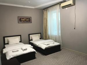 a hotel room with two beds and a window at Гостиница Райхан in Atyrau