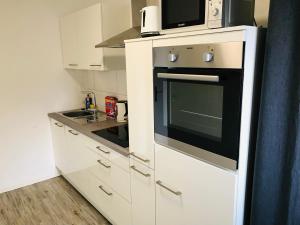 a white kitchen with a microwave and a stove at Generations Holiday Green Views in Attendorn