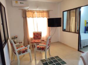 ein Wohnzimmer mit 2 Stühlen, einem Tisch und einem TV in der Unterkunft Apartamento amoblado 204 in Granada