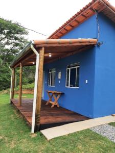 uma casa azul com um deque de madeira em Recanto em Cores - Chalé com uma linda vista para as montanhas em Córrego do Bom Jesus