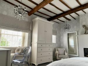 a bedroom with a bed and a dresser and chairs at Old Daltongate House in Ulverston