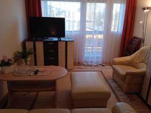 ein Wohnzimmer mit einem TV, einem Tisch und einem Sofa in der Unterkunft Fonyódi Centrum Apartman in Fonyód