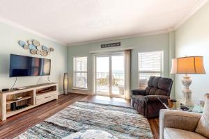 a living room with a tv and a couch and a chair at Paradise Shores 305 in Mexico Beach