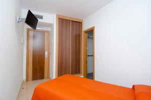 a bedroom with an orange bed and a television at Hostal Granado in Madrid