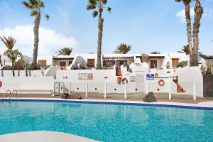 een zwembad voor een huis met palmbomen bij Puerto Chico 7 in Playa Blanca