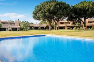 une grande piscine bleue en face d'une maison dans l'établissement Vilamoura Tenis 58, à Quarteira