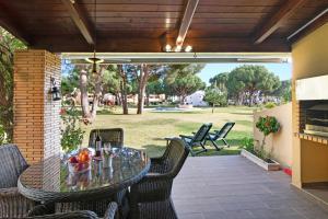 een patio met een tafel en stoelen en een grill bij Vilamoura Tenis 58 in Quarteira