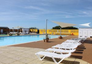 a row of white lounge chairs next to a swimming pool at Medmerry Park in Chichester