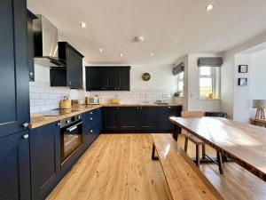 een keuken met blauwe kasten en een houten tafel bij Arrowan Common Farm Cottages in Coverack