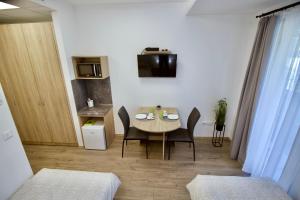 a small room with a table and chairs and a kitchen at Sport Centrum Apartman in Pápa