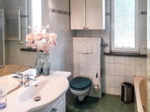 ein Badezimmer mit einem WC, einem Waschbecken und einer Vase aus Blumen in der Unterkunft Holiday Home Heike by Interhome in Wandlitz