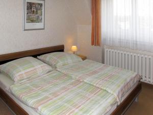 ein Bett mit gestreifter Decke in einem Schlafzimmer in der Unterkunft Apartment Am Park by Interhome in Raben Steinfeld