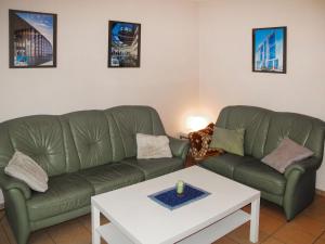 uma sala de estar com dois sofás verdes e uma mesa em Holiday Home Strandvilla - LUB117 by Interhome em Lubmin